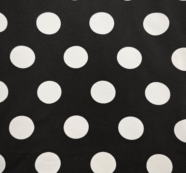 Black fabric with a white polka dot pattern, shown flat with a measuring ruler along the bottom edge to indicate scale.
