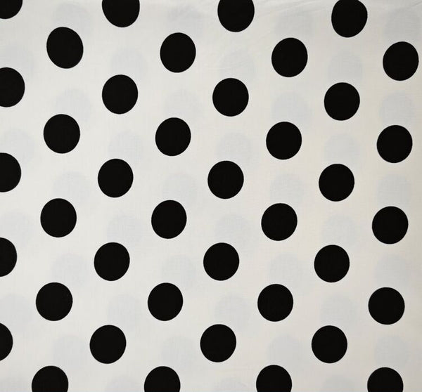 Black polka dot fabric pattern on a white background, shown with a wooden ruler at the bottom to indicate scale.